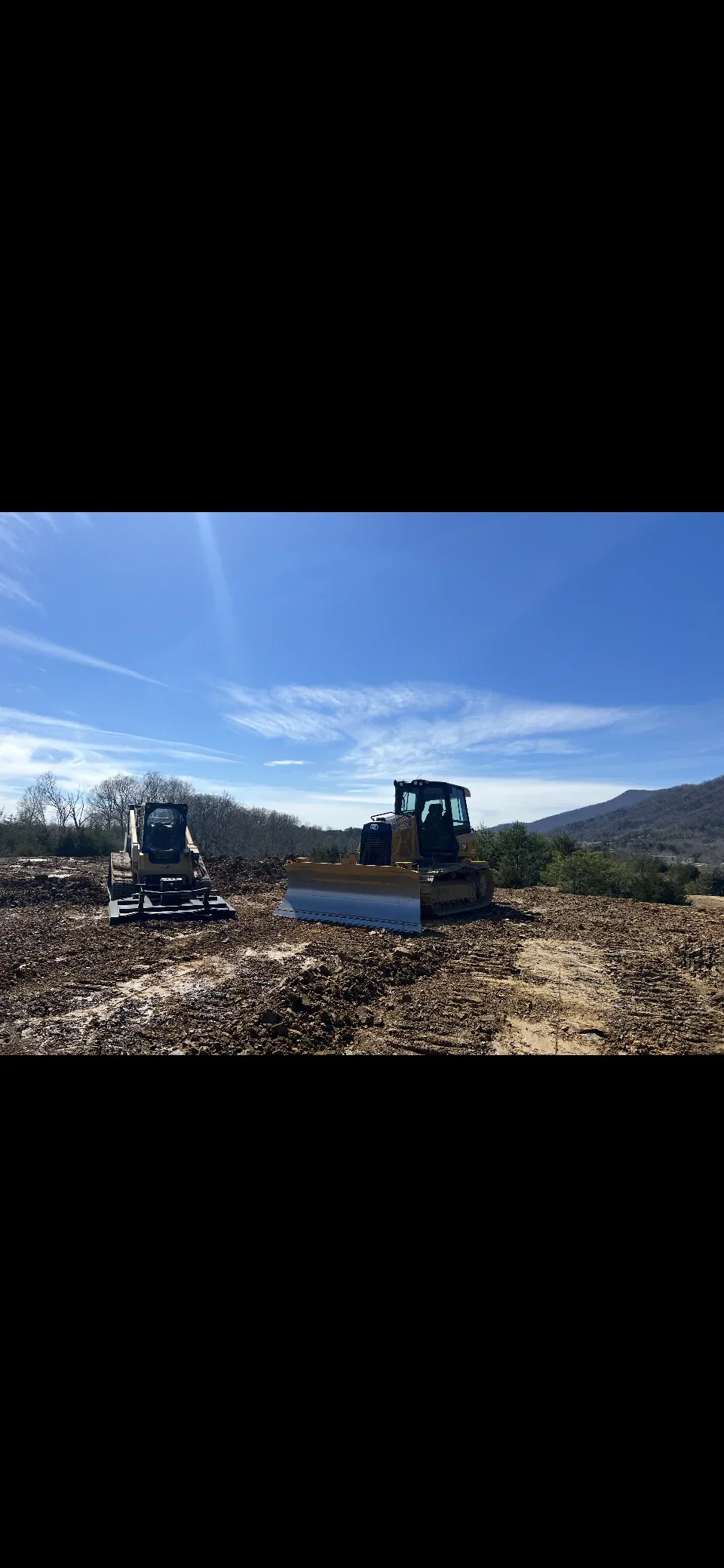 Dozer and track loader performing site grading on raw earth lot with aggregate base